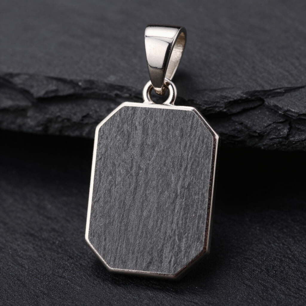 Monolith Alpha — slate pendant set in silver resting on raw slate